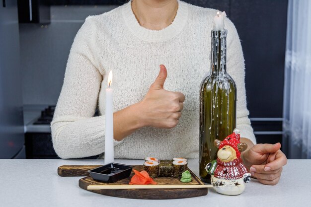 Rolinhos japoneses com peixe vermelho em uma caixa de papelão aberta Menina comendo sushi com pauzinhos Decoração de mesa