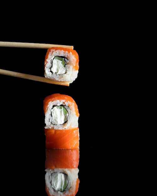 Roll mit Lachs in Stäbchen isoliert auf schwarz