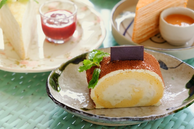 Rollen Sie Kuchen mit Puder der Schokolade, ein Stück in der Platte