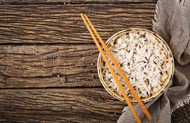 Rollen Sie mit gekochtem Reis auf einem Holztisch. Veganes Essen. Diätetische Mahlzeit. Ansicht von oben. Flach liegen