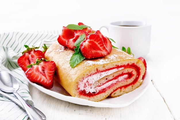 Rollen Sie mit Sahne und Erdbeermarmelade frische Erdbeeren und Minze in einer Tellerserviette und -löffeln auf Holzbretthintergrund Beschneidungspfad eingeschlossen