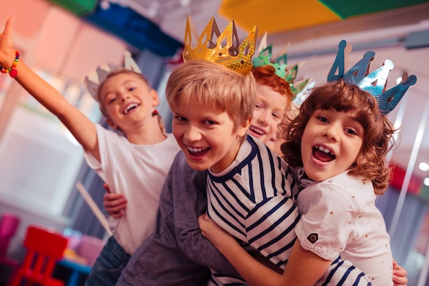 Rollen während des Spiels. Erfreute Kinder fühlen sich glücklich, während sie gemeinsam Geburtstag feiern