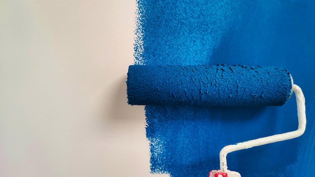 Roller con pintura azul en una pared blanca
