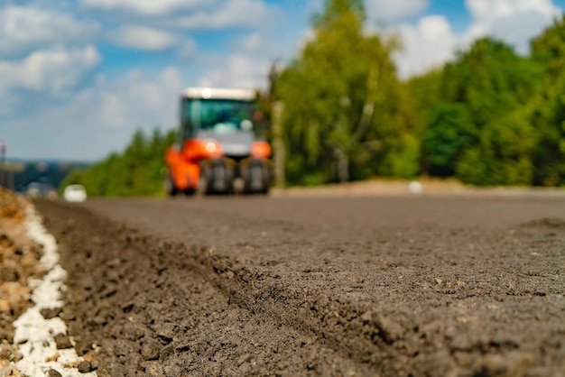 Roller verdichtet Asphalt auf der Straße während des Baus der Straße auf dem Hintergrund des blauen Himmels Verdichtung des Pflasters im Straßenbau