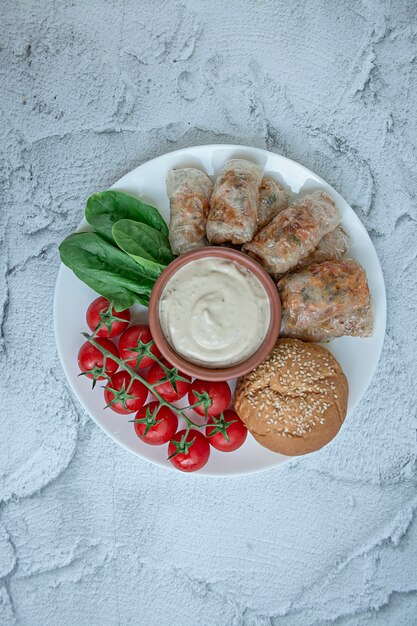 Rollito de primavera con carne y verduras servido en un plato blanco con salsa