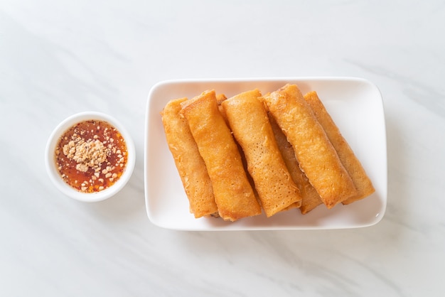 Rollito de primavera frito con salsa en la placa blanca.