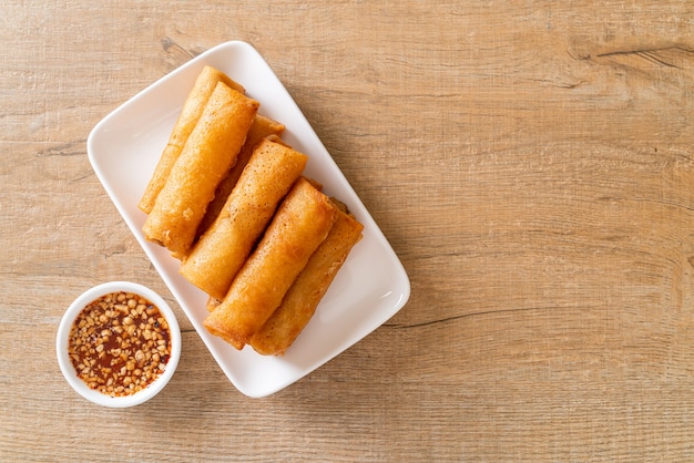 Rollito de primavera frito con salsa en la placa blanca.