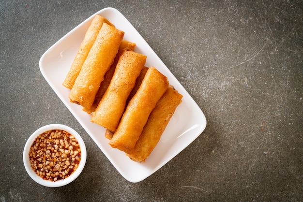 Rollito de primavera frito con salsa en la placa blanca.