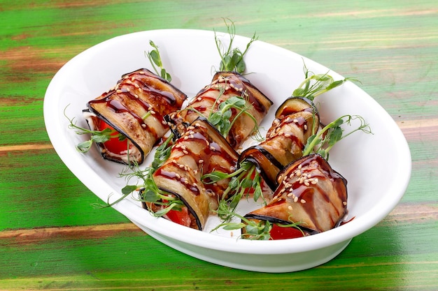 Rollitos de berenjena con salsa unagi Sobre un fondo de madera coloreada Plato vegetariano