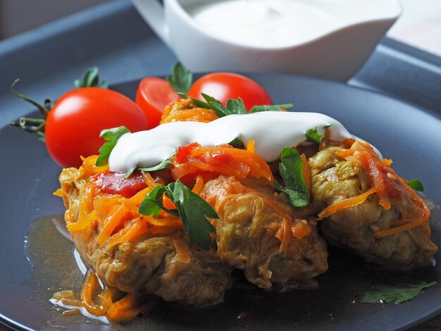 Rollitos de col con carne, arroz y verduras. Hojas de col de Pekín rellenas con carne, en salsa de tomate, sobre un plato negro. . Chow Farchi, dolma, Sarma, rollitos de col o golabki. Vista superior,