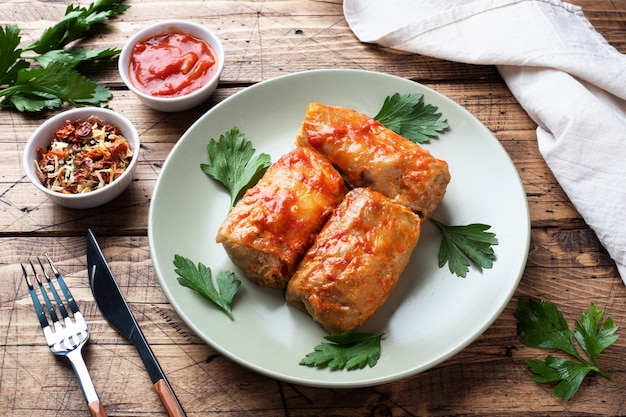 Rollitos de col con carne, arroz y verduras en el plato. Hojas de col rellenas con carne. Fondo de madera