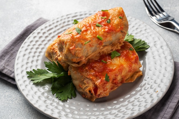 Rollitos de col con carne, arroz y verduras en el plato. Hojas de col rellenas con carne. Mesa de hormigón gris