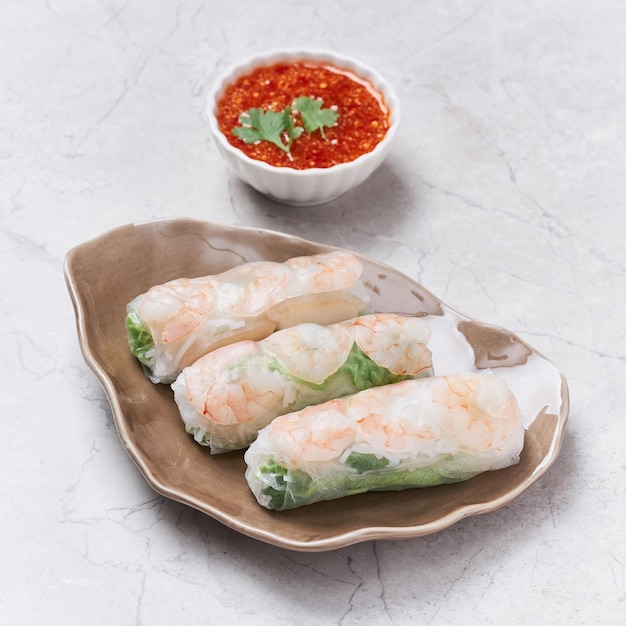 Rollitos de primavera frescos con salsa picante servidos en un plato aislado en una vista lateral de fondo gris de la comida vietnam