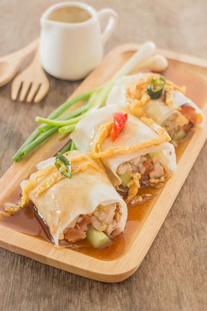 Rollitos de primavera con verduras y pollo en plato de madera.