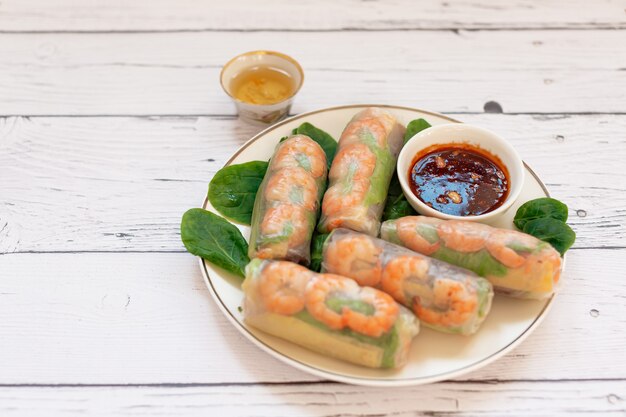 Rollitos de primavera vietnamitas con pollo tierno langostinos tigre fideos de arroz mango jugoso hierbas frescas sobre una tabla de madera salsa de sésamo