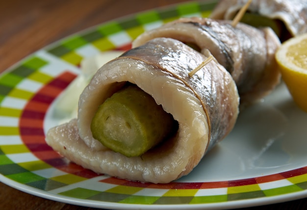 Rollmops: filetes de arenque en escabeche, rodajas de cebolla enrolladas, pepinillo en escabeche.