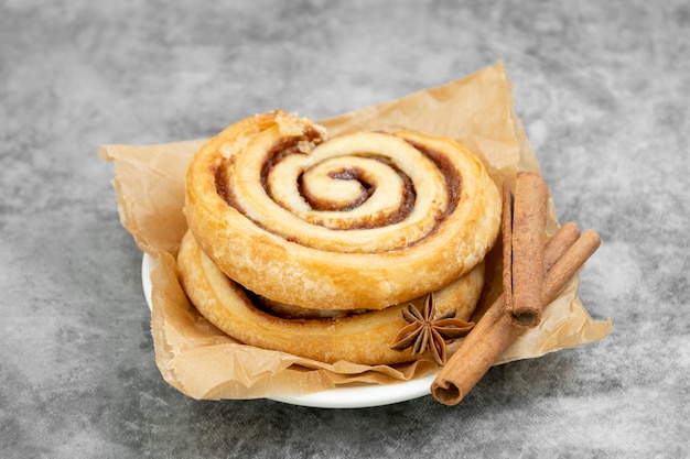 Rollo de canela con palitos de canela en la mesa de madera, pasteles daneses, pasteles dulces para el desayuno o merienda.