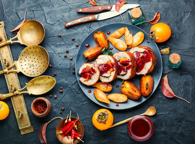 Rollo de cerdo al horno con caqui de otoño.Carne rellena con frutas.Alimentos de otoño.