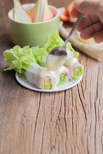rollo de ensalada de atún en placas blancas en la mesa de madera vieja.