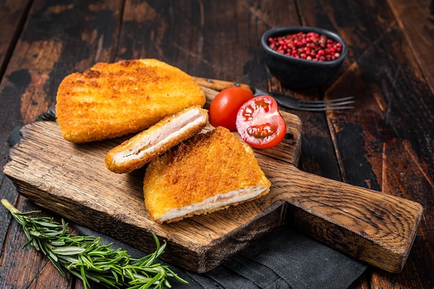 Rollo de filete de pollo Cordon Blue crujiente con jamón y queso servido en una tabla de madera Fondo de madera Vista superior