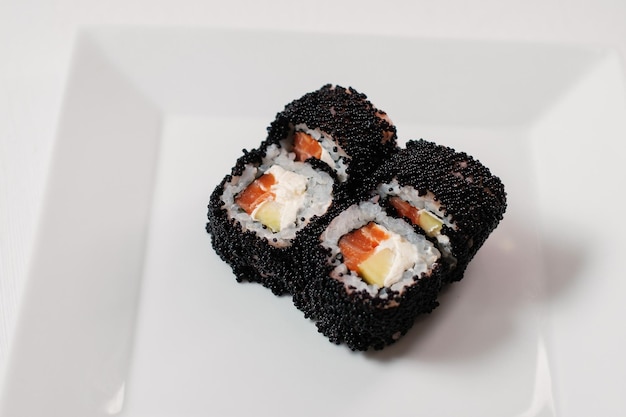 Rollo maki de sushi de caviar rojo servido en plato blanco