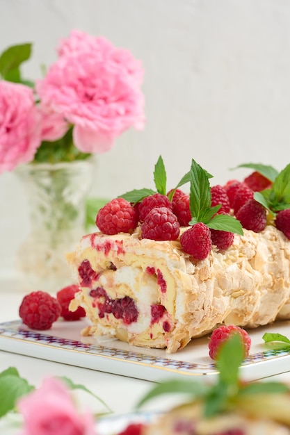 Foto rollo de merengue al horno con crema y fondo blanco de frambuesa roja fresca