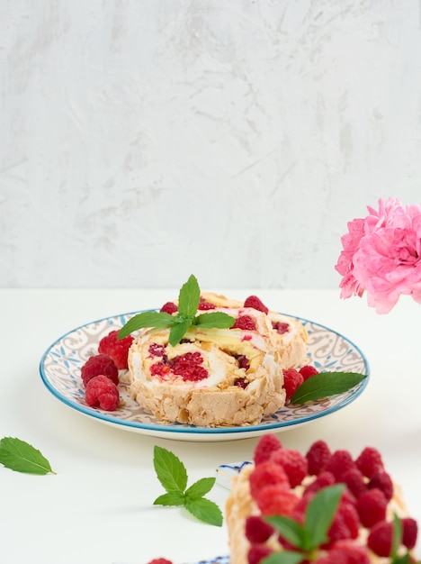 Rollo de merengue al horno con nata y frambuesa roja fresca