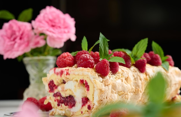 Rollo de merengue al horno con nata y frambuesa roja fresca