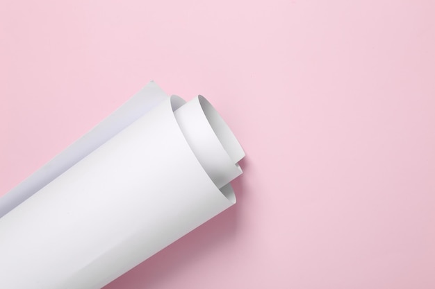 Rollo de papel blanco enrollado sobre un fondo rosado Maqueta para el diseño