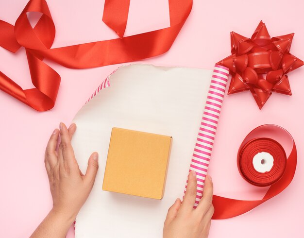 Rollo de papel para envolver, caja y cinta de seda roja con lazo y artículos para envolver regalos