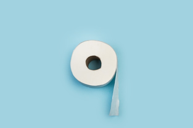 Rollo de papel higiénico sobre un fondo azul claro en una vista superior