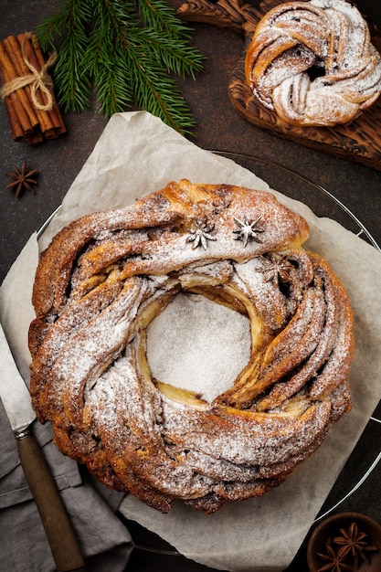 Rollo de pastel de Navidad con canela y azúcar en polvo sobre un hormigón viejo oscuro