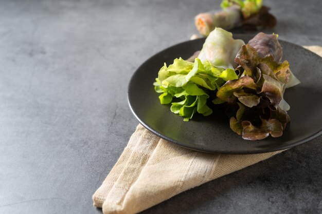 Rollo de primavera de vegetales frescos, comida limpia, ensalada para perder peso, sobre fondo oscuro