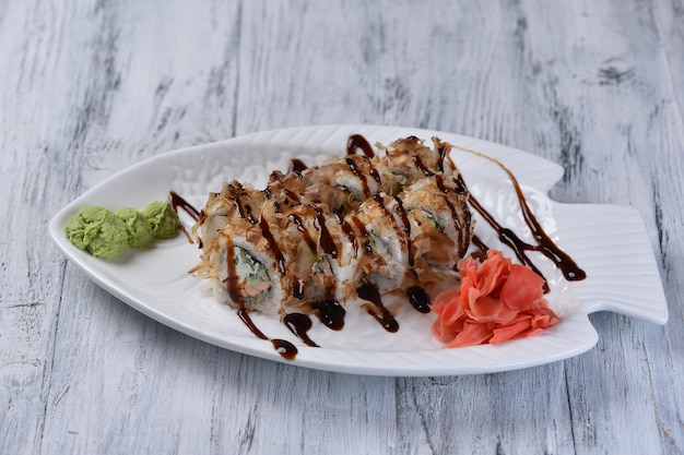 Rollo de salmón y virutas de atún cubierto de salsa. Plato japonés sobre una mesa gris. Vista superior