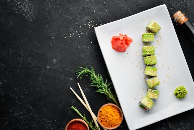 Rollo de sushi con aguacate, pepino y tomate Cocina japonesa Vista superior Sobre un fondo negro