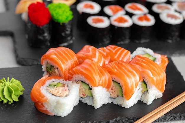 Rollo de sushi cubierto con salmón fresco servido en plato