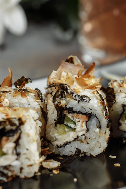 Rollo de sushi de dragón dorado con anguila de atún, pepino, semillas de sésamo y caviar tobiko sobre fondo de madera