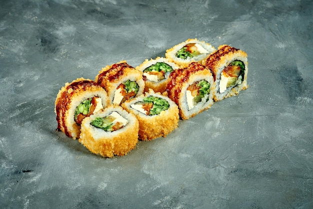 Rollo de sushi empanado con pepino de anguila sobre un fondo gris Menú de sushi de enfoque selectivo