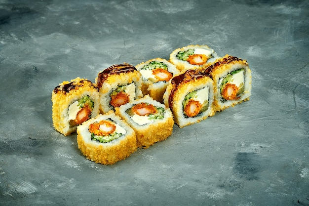 Foto rollo de sushi empanado con pepino de camarones sobre un fondo gris ruido del menú de sushi de enfoque selectivo agregado en la postproducción