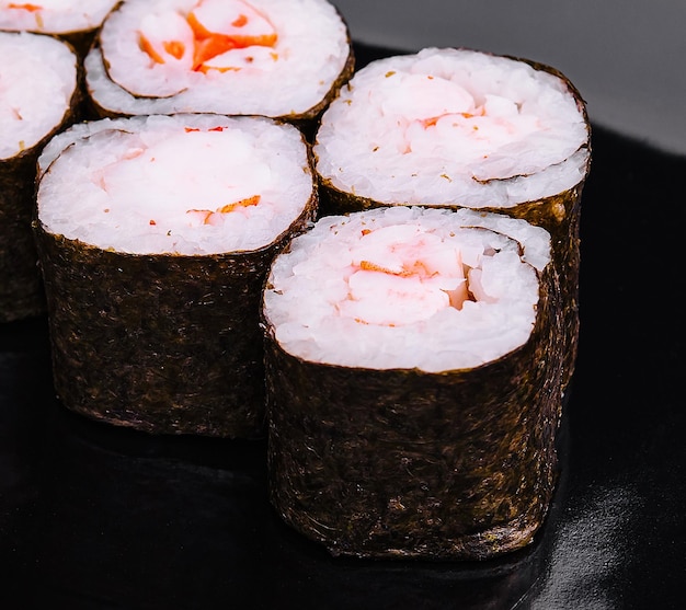 un rollo de sushi maki con camarones en un plato negro