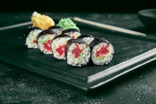 Rollo de sushi maki con salmón. Cocina japonesa clásica. Entrega de comida. Fondo negro