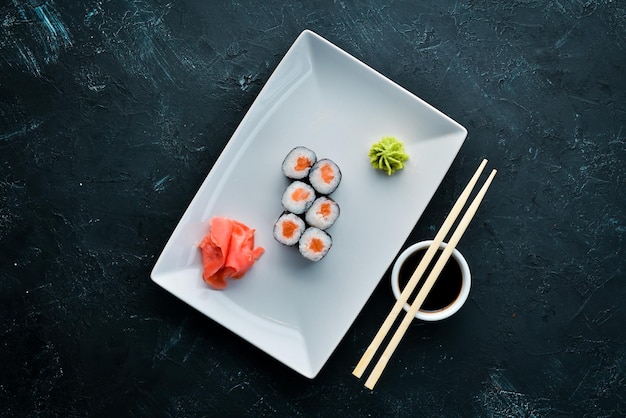 Rollo de sushi maki con salmón Cocina japonesa Vista superior Sobre un fondo de piedra negra