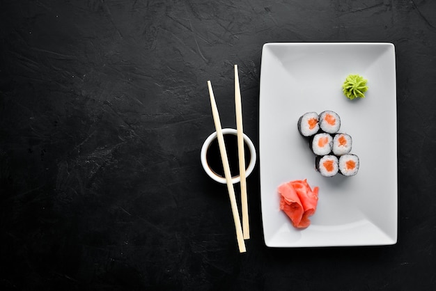 Rollo de sushi maki con salmón Cocina japonesa Vista superior Sobre un fondo de piedra negra