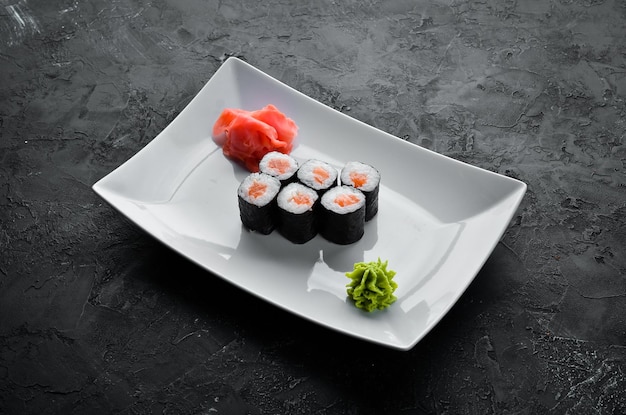 Rollo de sushi maki con salmón Cocina japonesa Vista superior Sobre un fondo de piedra negra