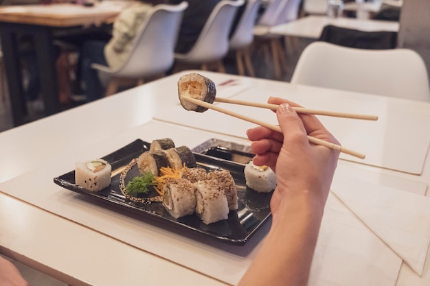 Un rollo de sushi con palillos chinos en una foto de un restaurante