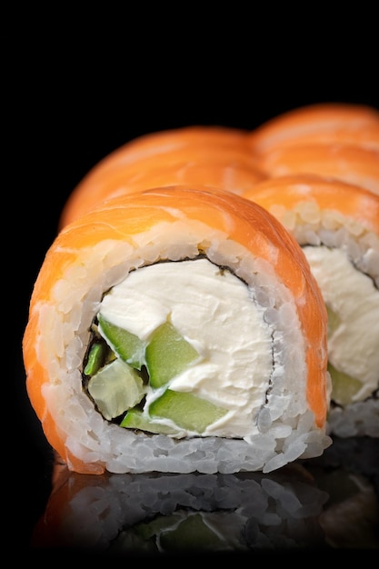 Rollo de sushi Philadelphia con queso crema de aguacate, gambas y salmón sobre fondo negro Menú de sushi