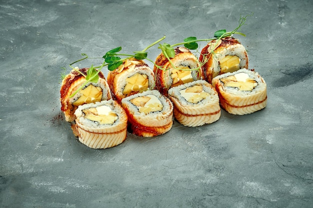 Rollo de sushi con plátano de anguila y queso crema sobre fondo gris Enfoque selectivo Menú de sushi