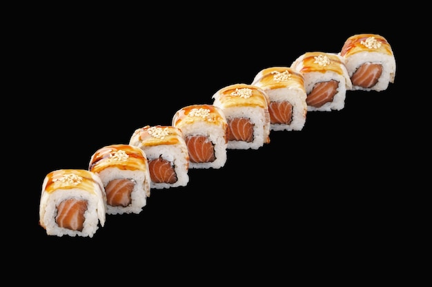 Rollo de sushi con salmón, anguila, mayonesa japonesa, salsa unagi, sésamo y vieira aislado en negro