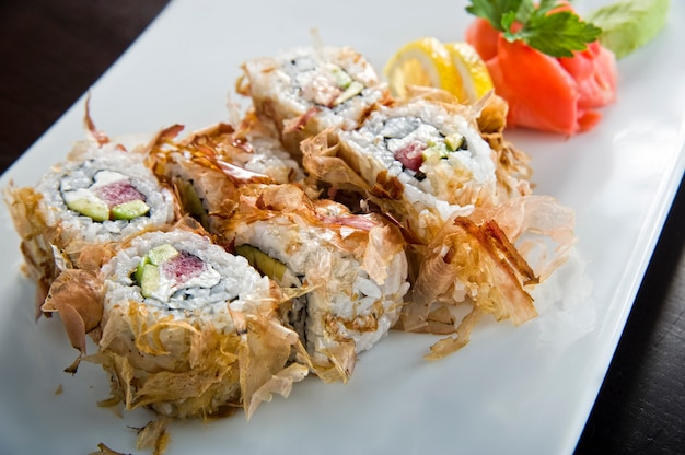 Rollo de sushi con salmón y camarones tempura.