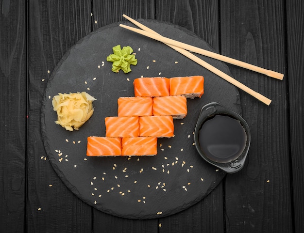 Rollo de sushi con salmón, queso crema en negro.